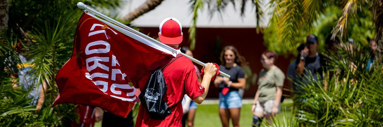 Student Holding 澳门真人真钱平台登录 Flag on College Colors Day